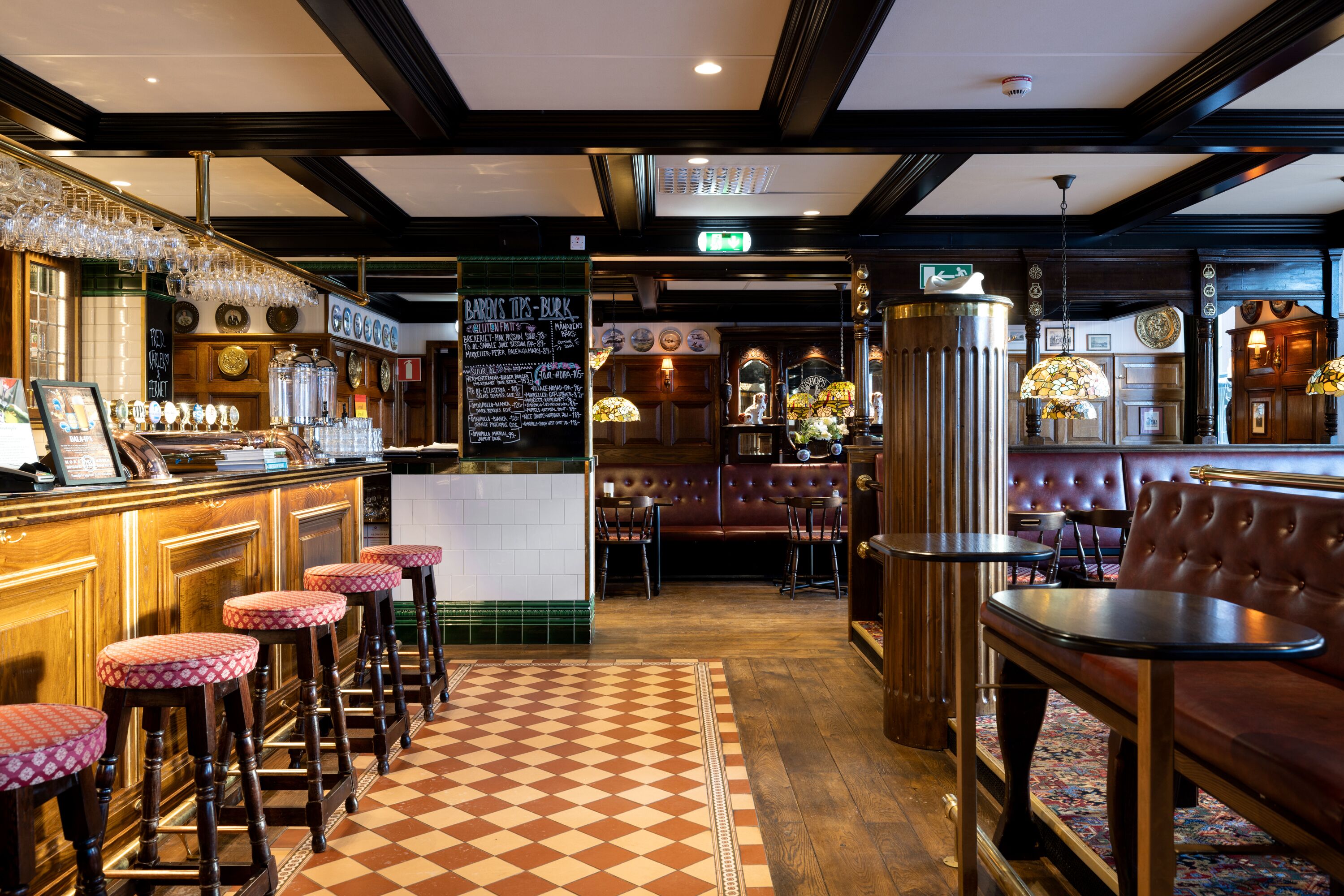 A bar area with stools, a checkered floor, and a seating area with tables and chairs.