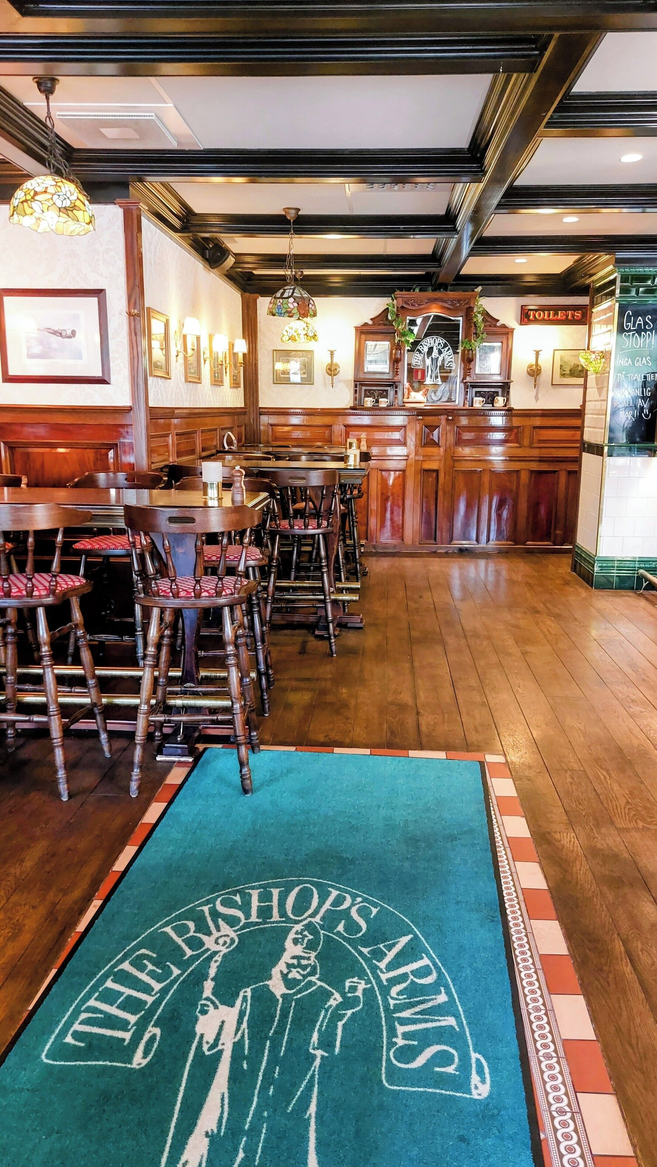 A restaurant with wooden furniture, a bar area, and a sign reading "TOILETS".