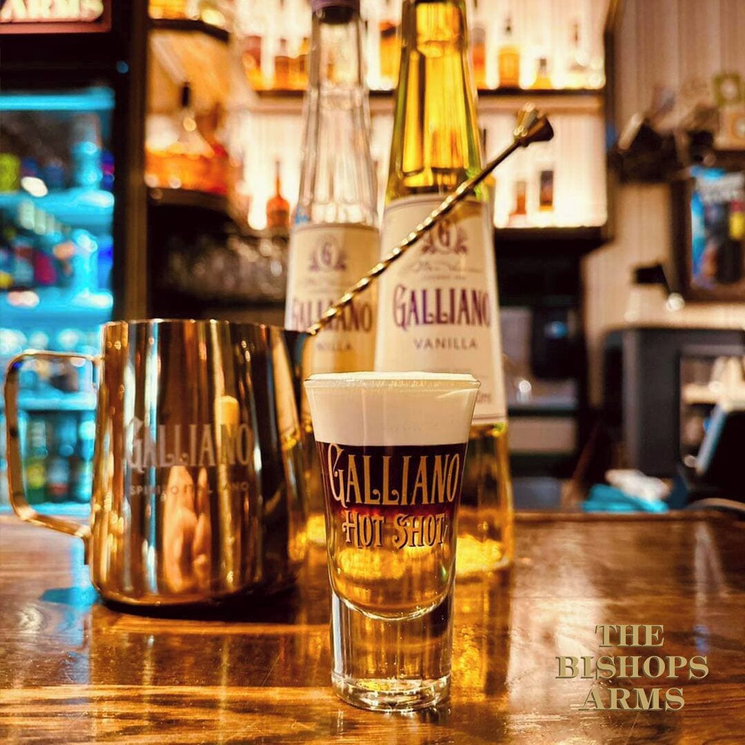 En bardisk med ett litet glas märkt "Galliano Hot Shot" och en flaska Galliano.