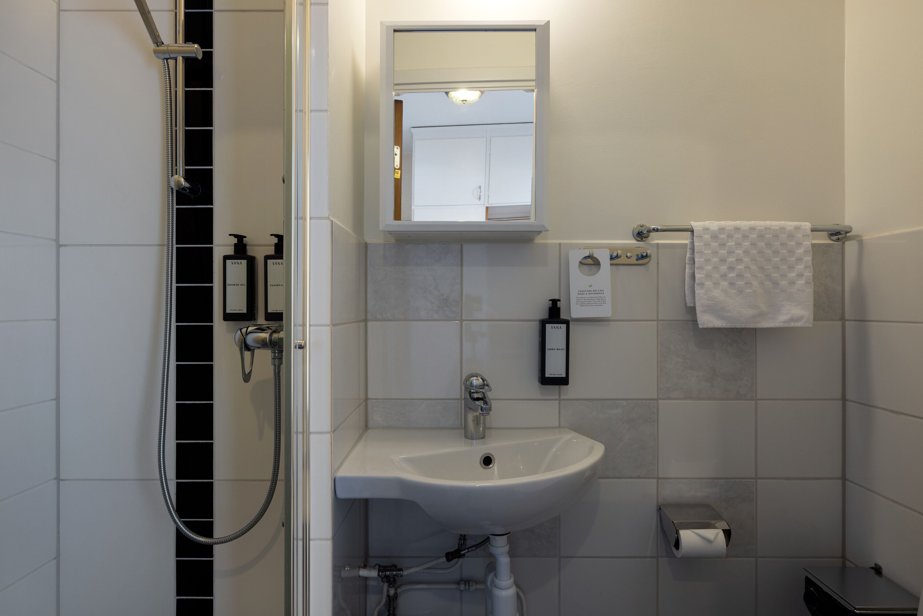 A bathroom with a shower, sink, and towel rack.