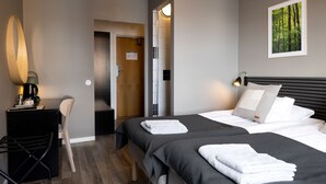 A hotel room with a bed, a desk with a lamp, a chair, and a painting on the wall. - Hotel Bishops Arms Mora (Mora)