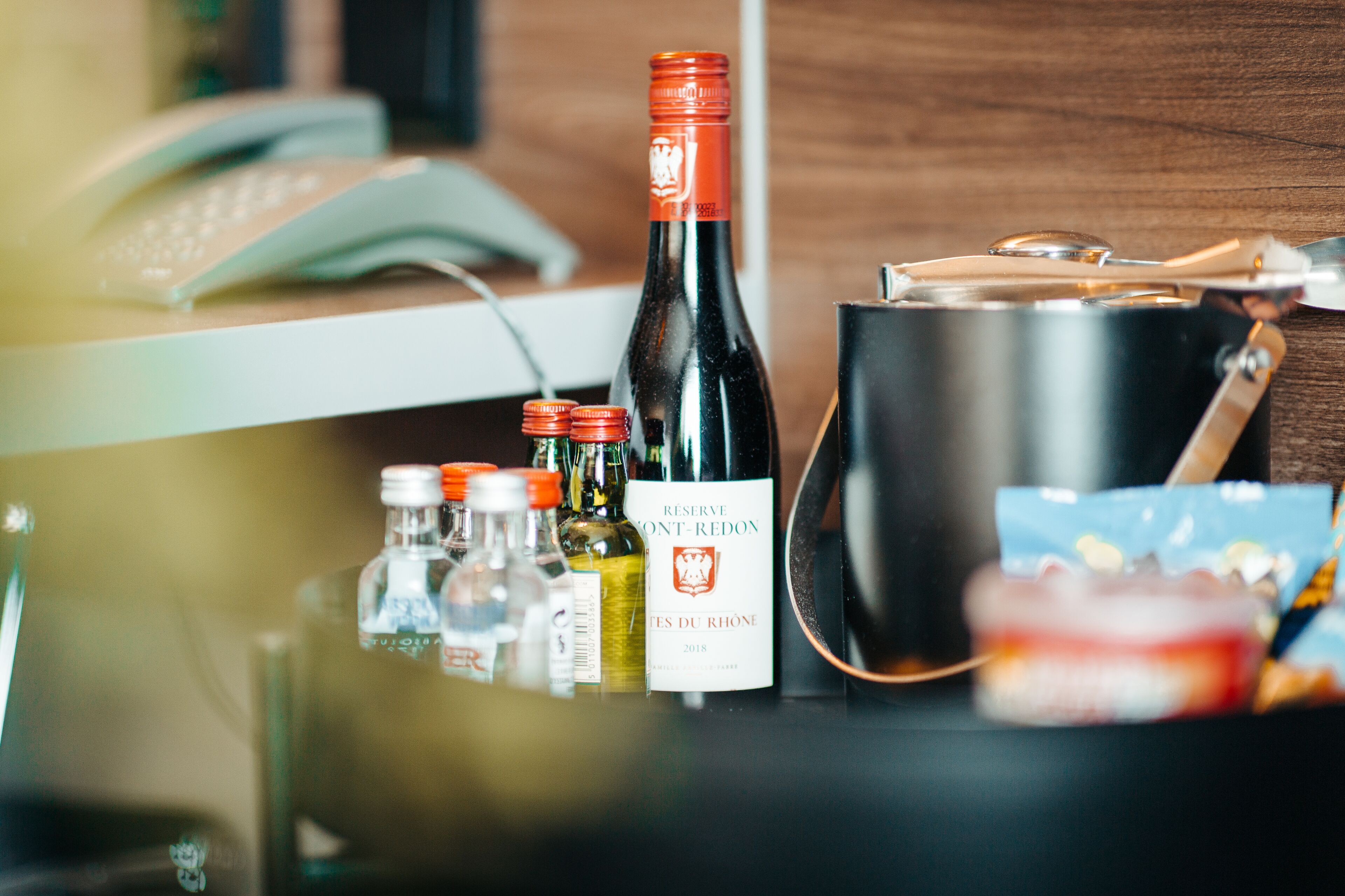Een fles wijn, een thermosfles en een handtas op een tafel.