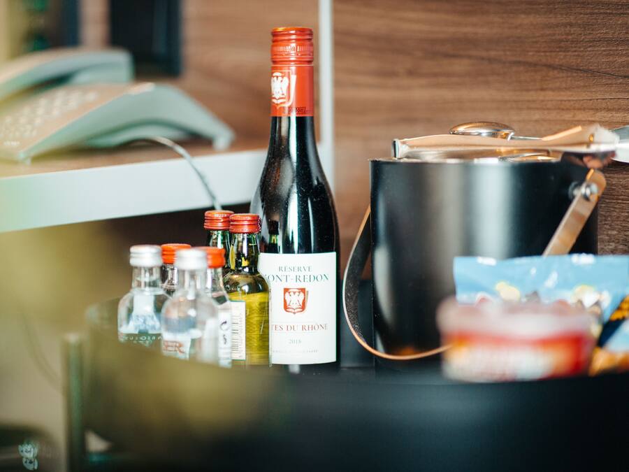 Een fles wijn, een thermosfles en een handtas op een tafel.