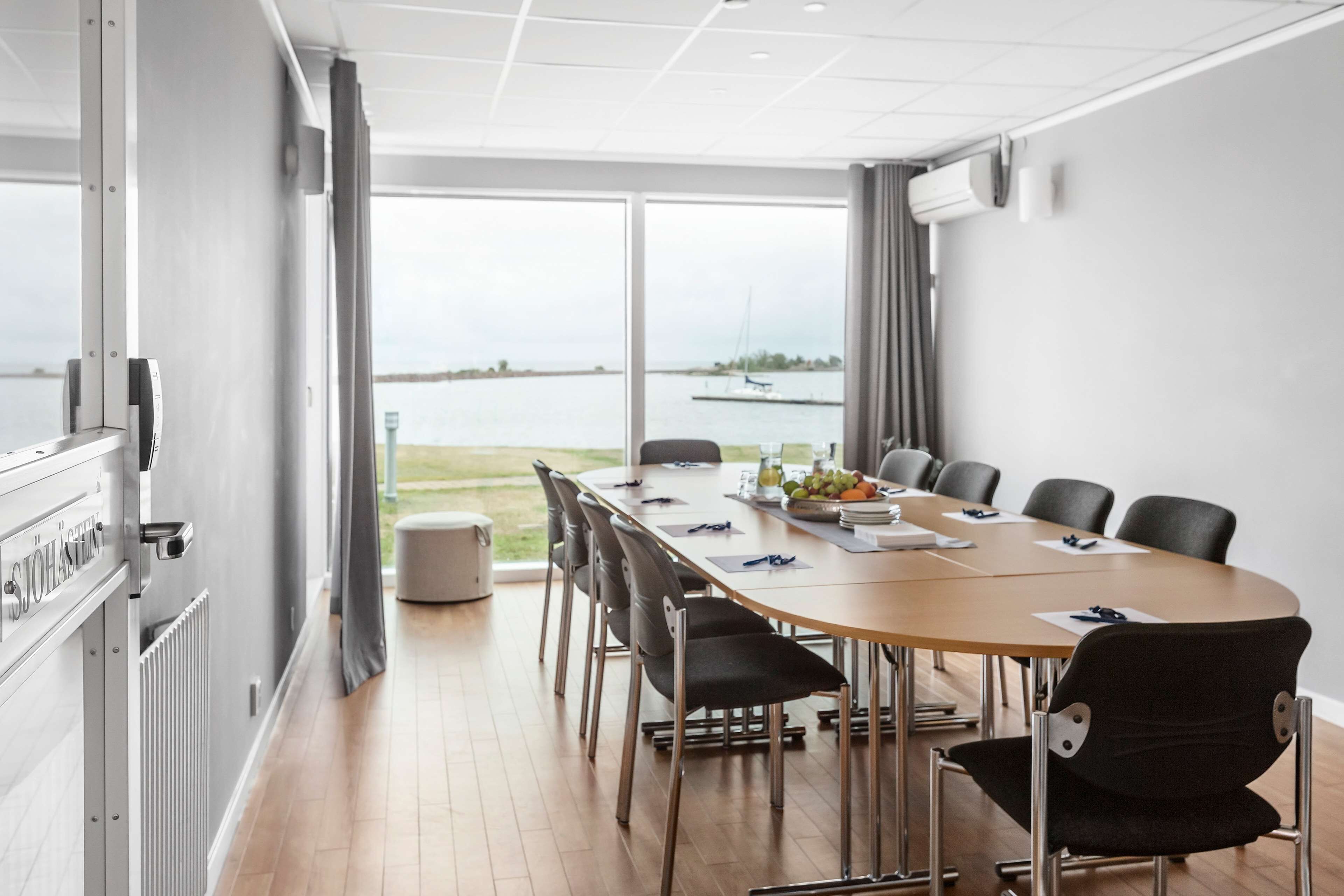 A conference room with a large table, chairs, and a view of the water.