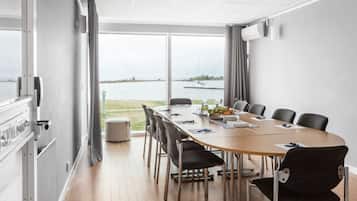 A conference room with a large table, chairs, and a view of the water.