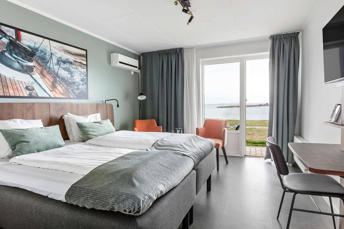 Une chambre d’hôtel moderne avec un grand lit, un bureau et une vue sur la mer.