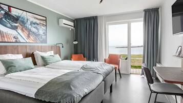 Una habitación de hotel moderna con una cama grande, un escritorio y vistas al mar.