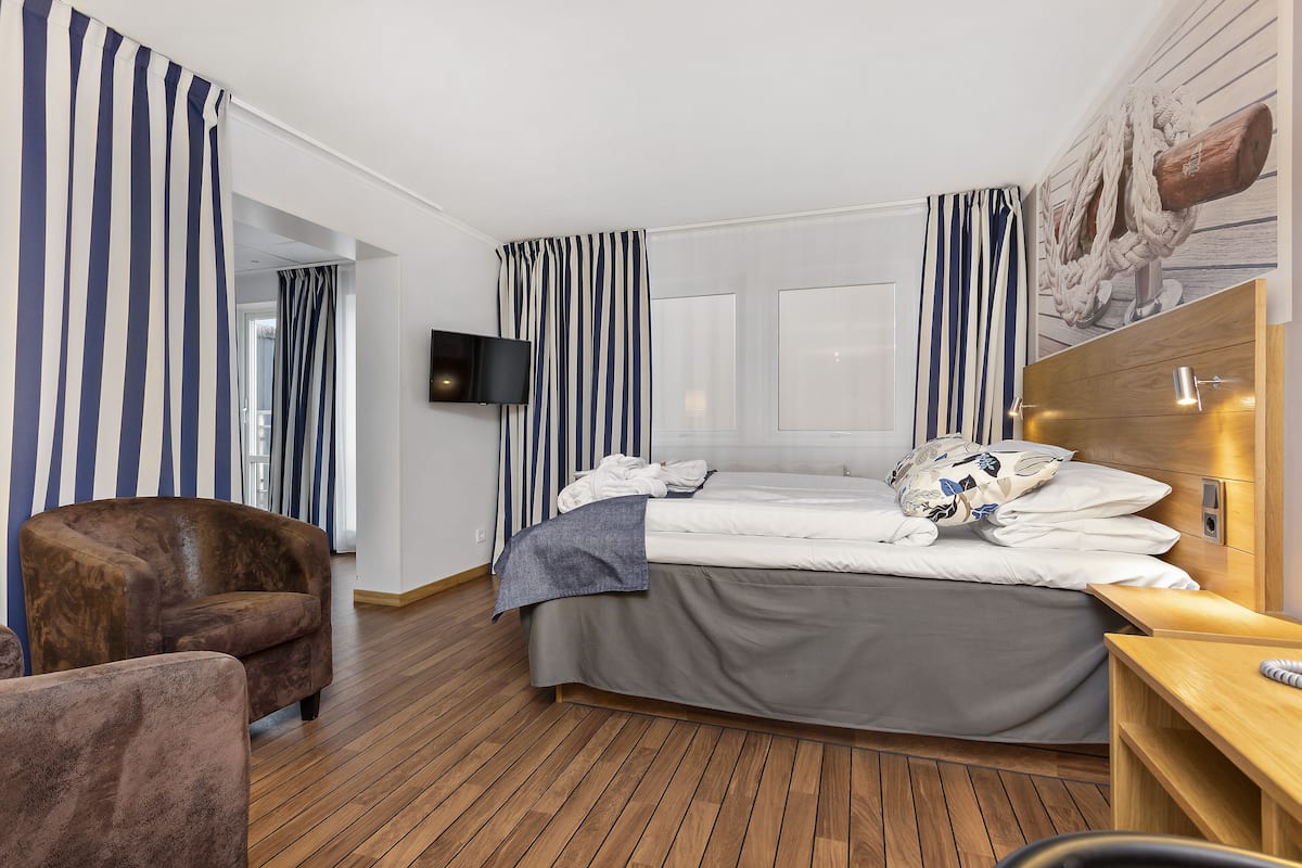 Une chambre d’hôtel avec un lit, une chaise, une télévision et un plancher en bois.