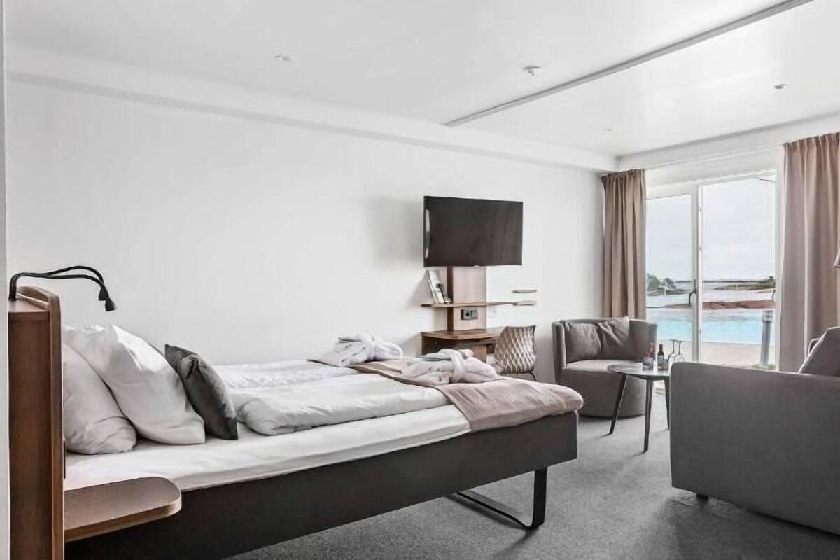 Ein Hotelzimmer mit Bett, Schreibtisch, Stuhl, Fernseher und Blick auf einen Pool.