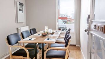 Een vergaderzaal met een lange tafel, zwarte stoelen en uitzicht buiten door een deur.