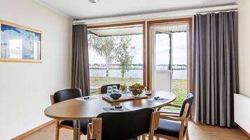 A dining area with a table, chairs, and a view of a body of water through large windows.