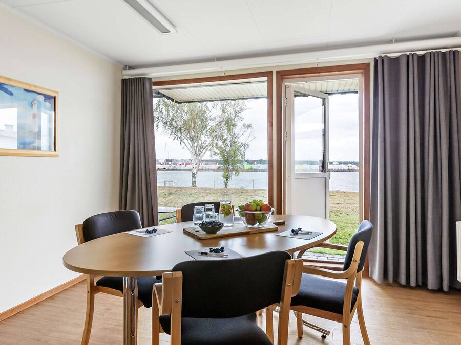 A dining area with a table, chairs, and a view of a body of water through large windows.
