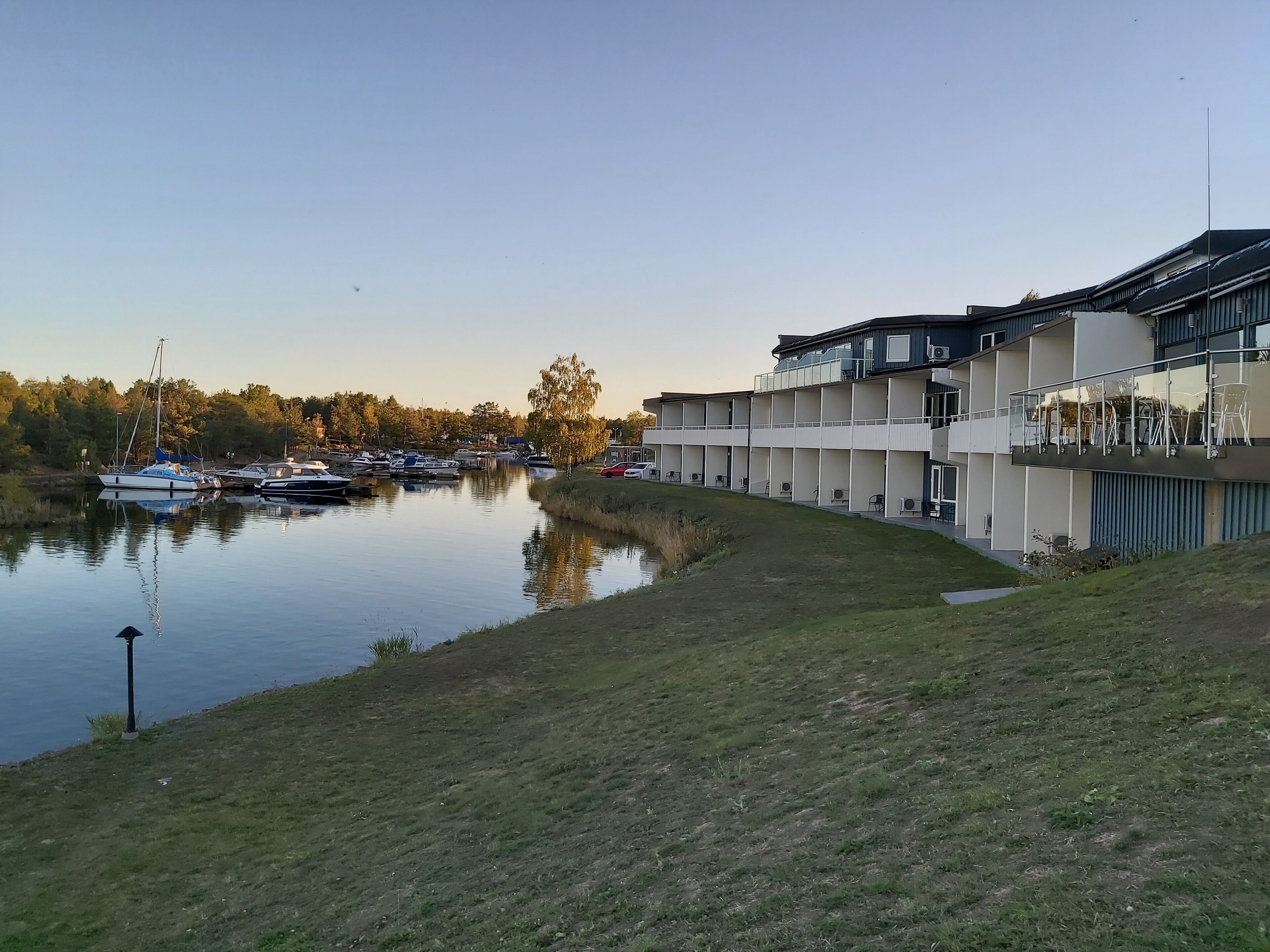 A waterfront property with a grassy area, a body of water, and a modern building with multiple balconies.