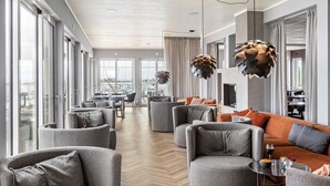 Ein großzügiger Wohnbereich mit modernem Design, inklusive einer großen Couch, Sesseln und einem Esstisch.