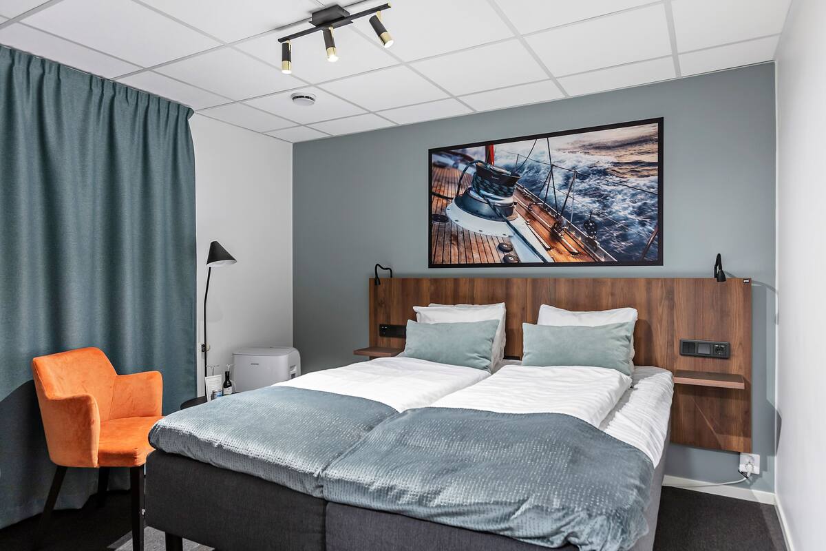 Une chambre d’hôtel moderne avec un grand lit, un bureau, une chaise et un tableau au mur.