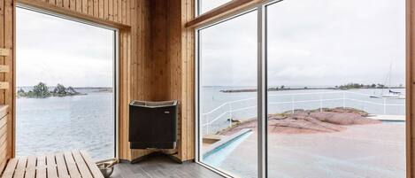 A wooden interior with large windows overlooking a pool and water body.