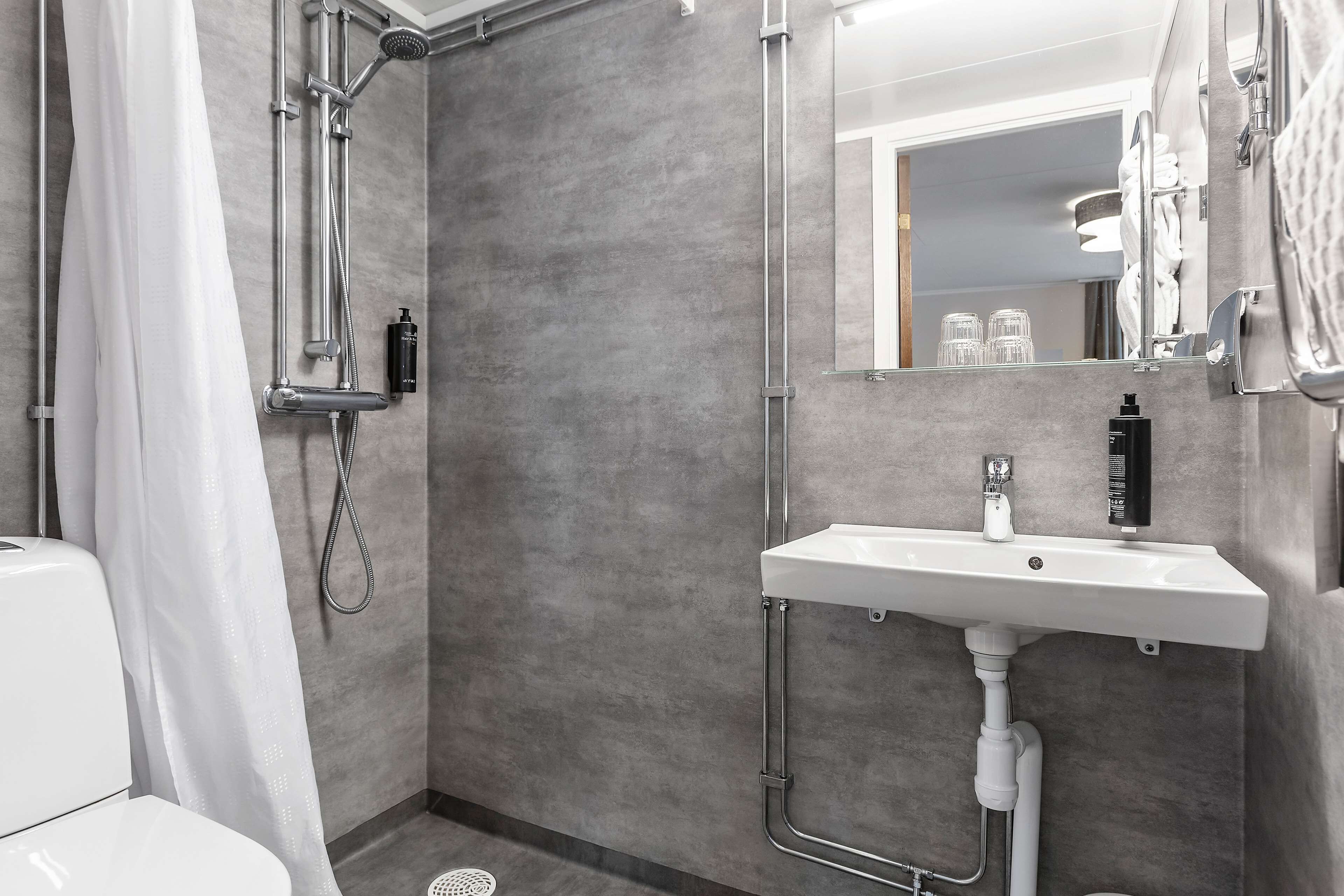 A modern bathroom with a shower, sink, and toilet.