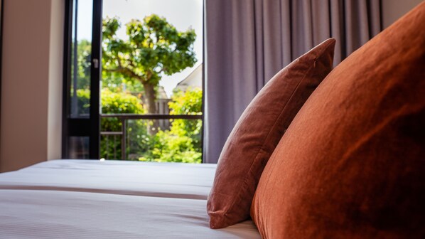 A hotel room with a large window, a bed with white linens, and two brown pillows. - Home Hotel Carlscrona (Karlskrona)