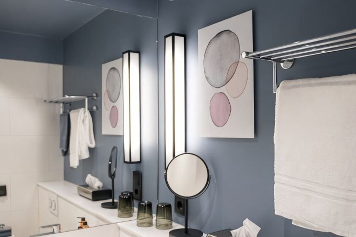 Une salle de bain moderne avec un miroir, un porte-serviettes et une œuvre d’art accrochée au mur.