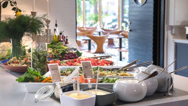 A buffet table with various food items and condiments, including salads, fruits, and sauces. - Home Hotel Carlscrona (Karlskrona)