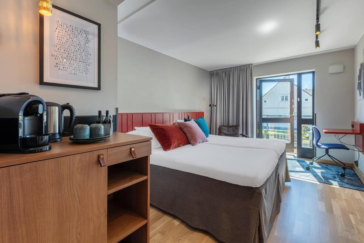 Ein Hotelzimmer mit Bett, Schreibtisch mit Kaffeemaschine, Stuhl und Blick nach draußen.
