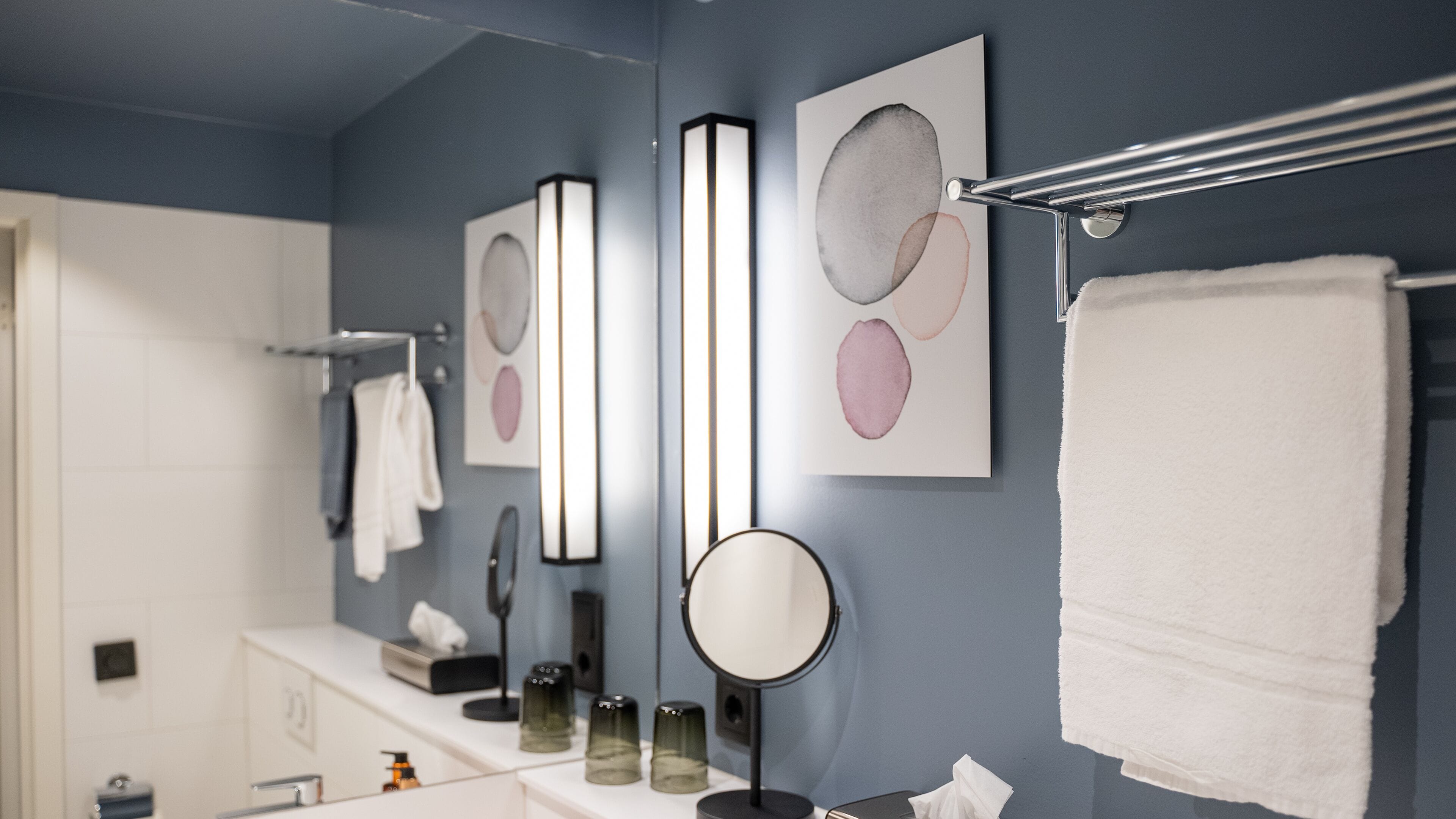 A bathroom with a white sink, a mirror, and a towel rack.