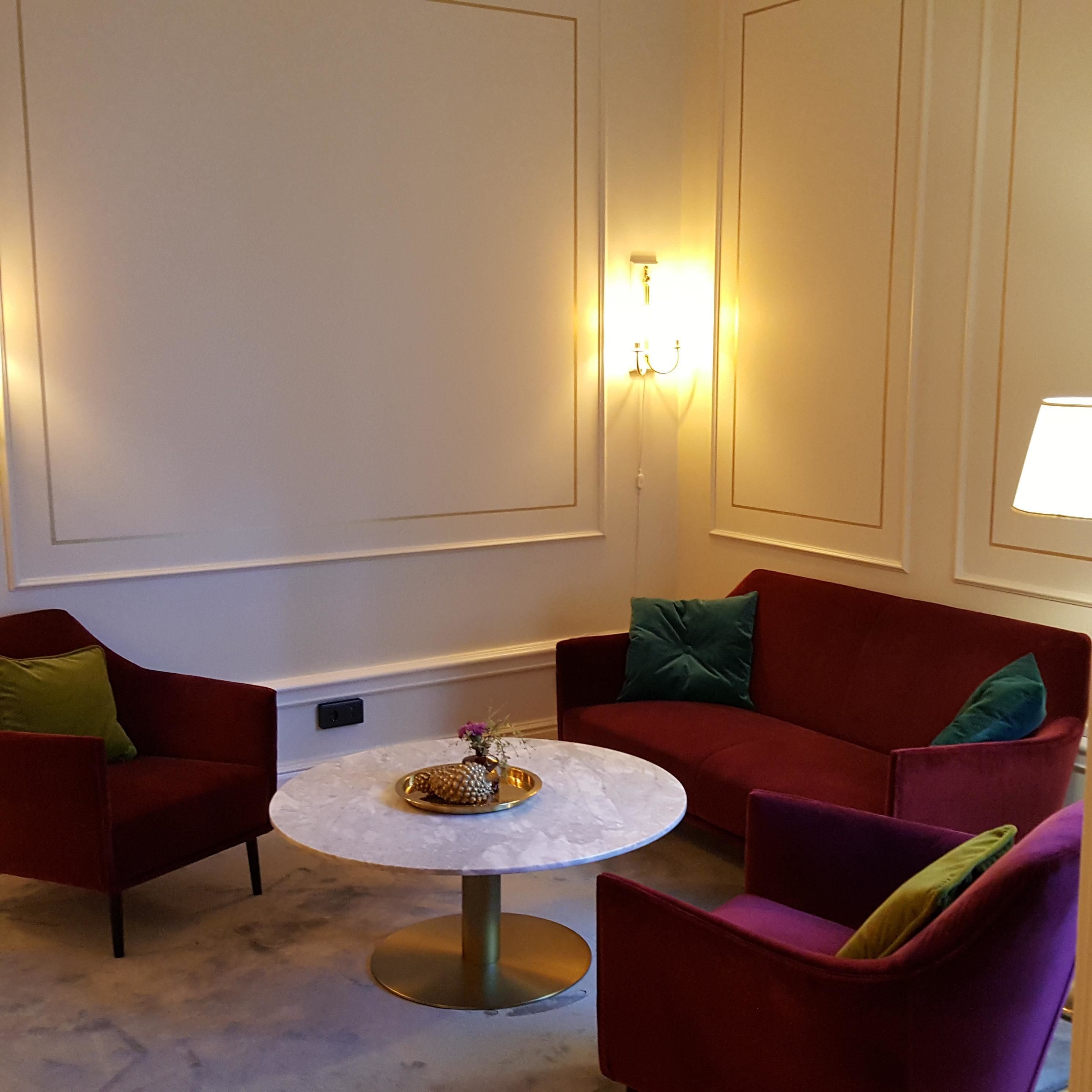 A room with a round table, two red armchairs, and a red sofa.