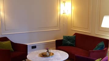 A room with a round table, two red armchairs, and a red sofa.