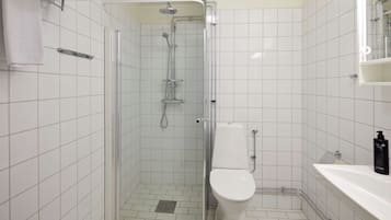 Un baño con ducha de vidrio, inodoro y lavabo con espejo.