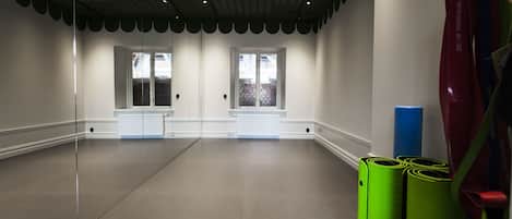 A spacious room with a large window, a radiator, and exercise equipment.
