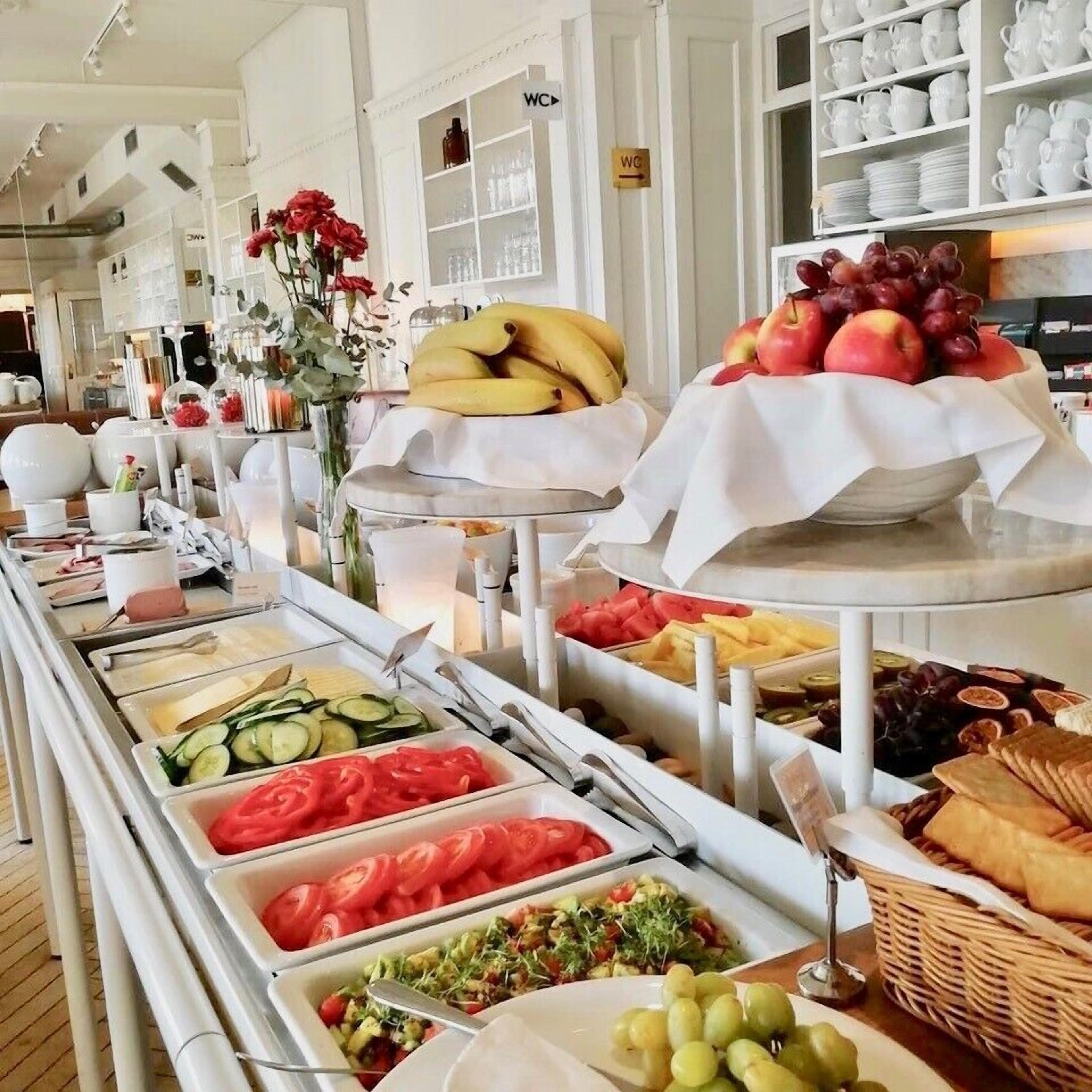 A buffet with various food items including fruits, vegetables, and bread.