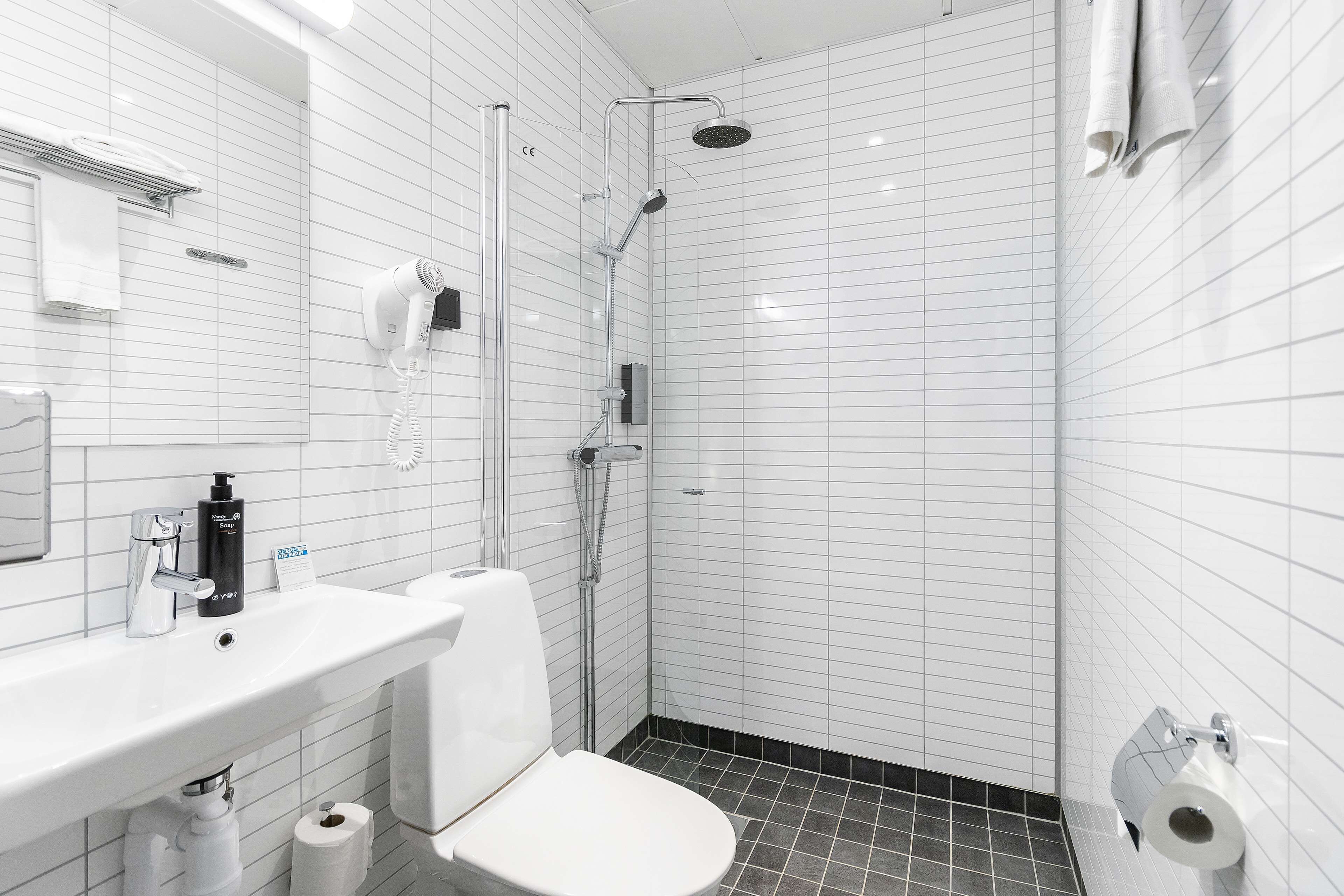 A modern bathroom with a white sink, toilet, and shower.