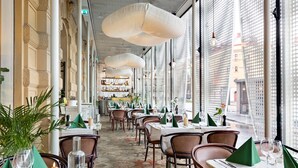 A restaurant with tables set for dining, large windows, and hanging light fixtures. - Best Western Plus Hotel Baltic (Sundsvall)