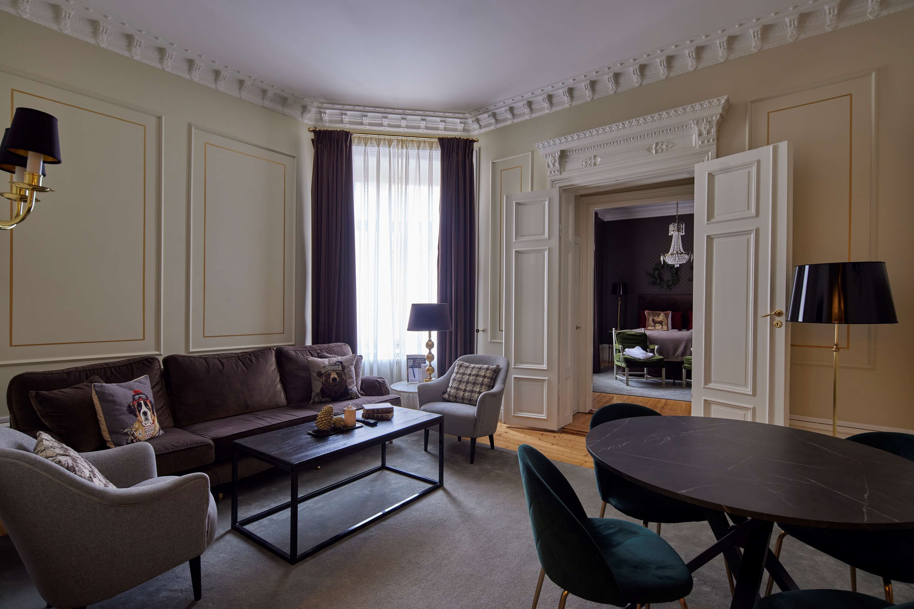 A living room with a sofa, armchairs, a coffee table, and a dining table.