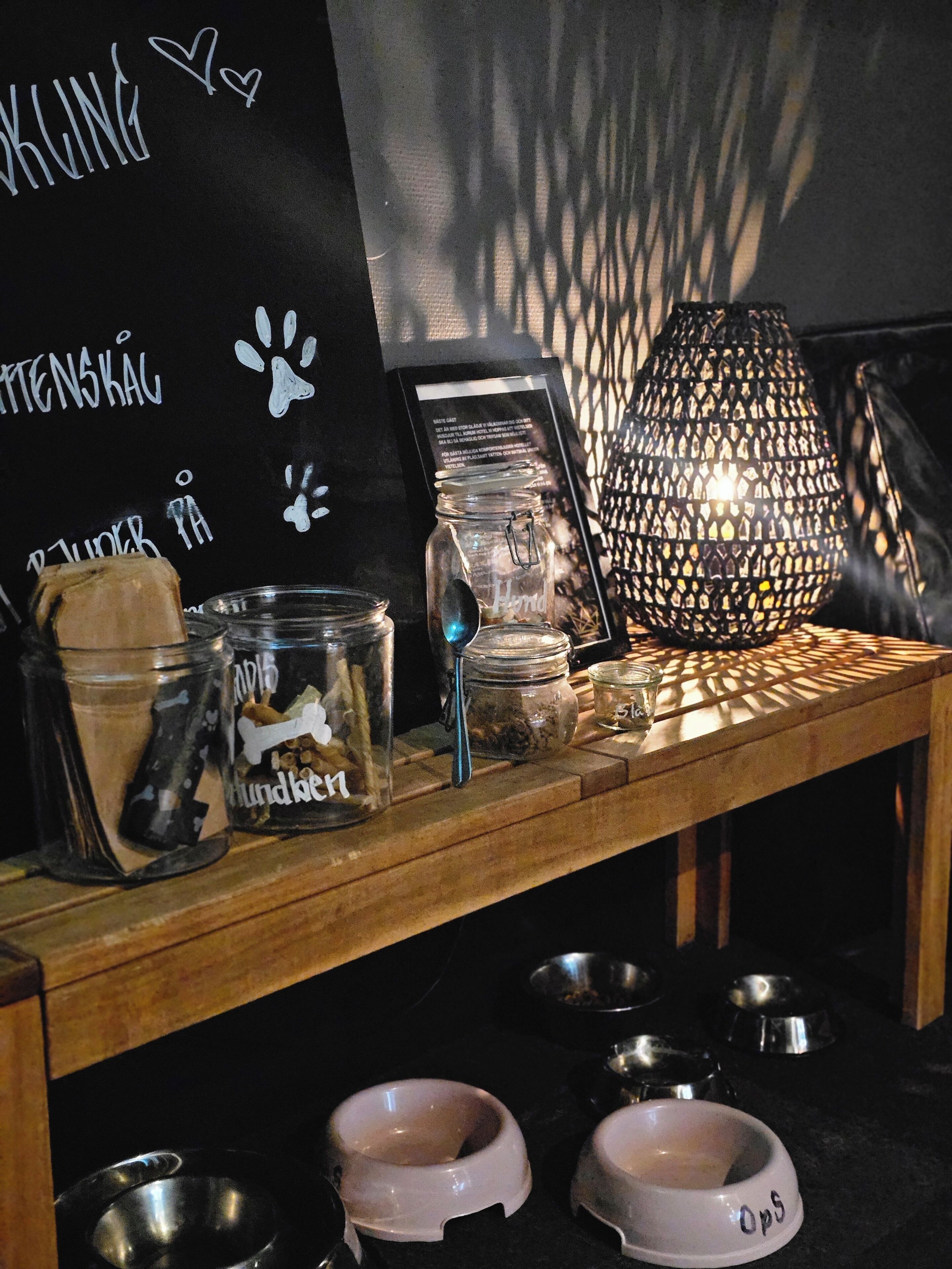 A wooden table with glass jars, a metal bowl, and a decorative lamp.