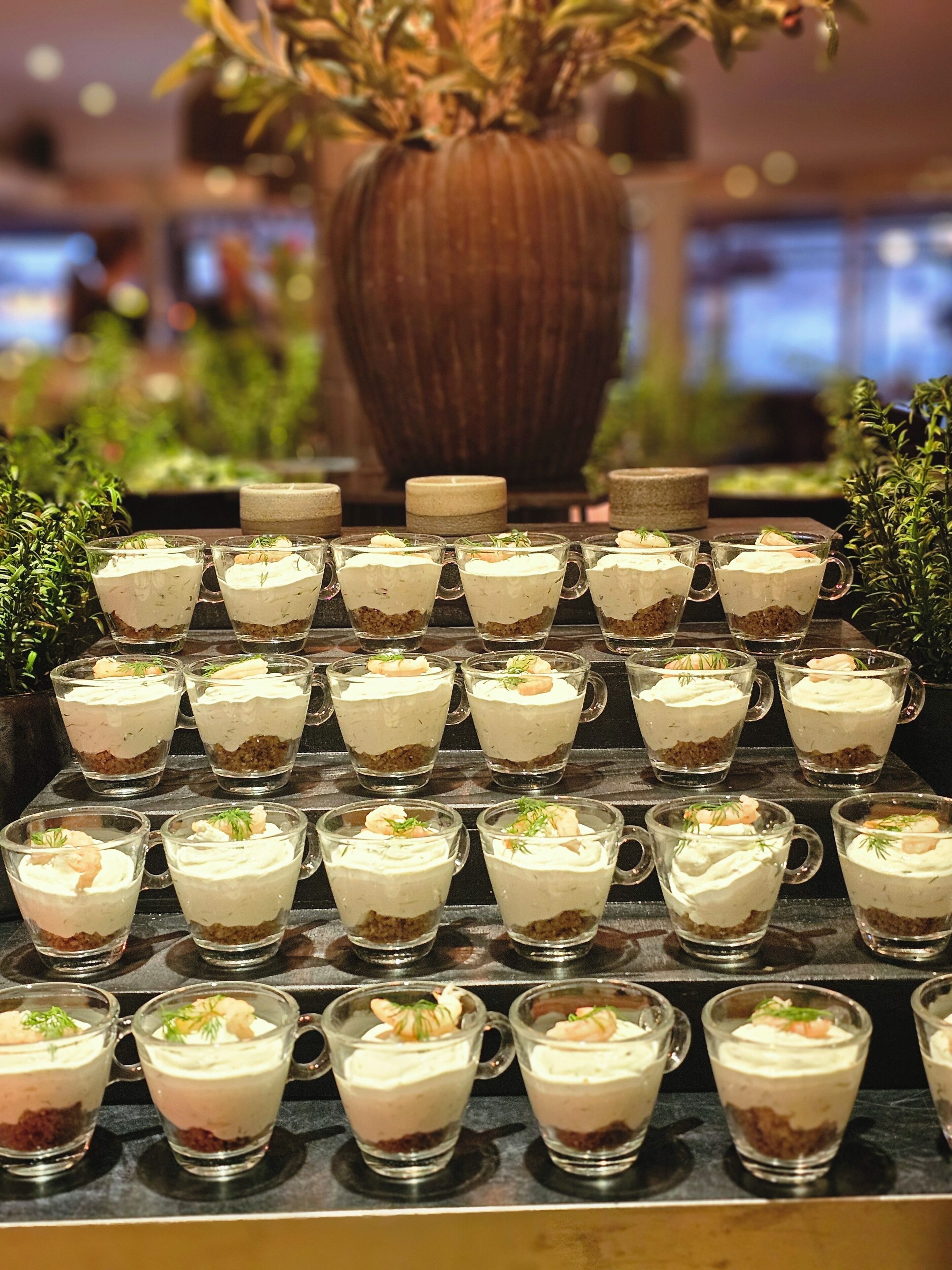 A tiered dessert display with multiple glass cups arranged in rows.