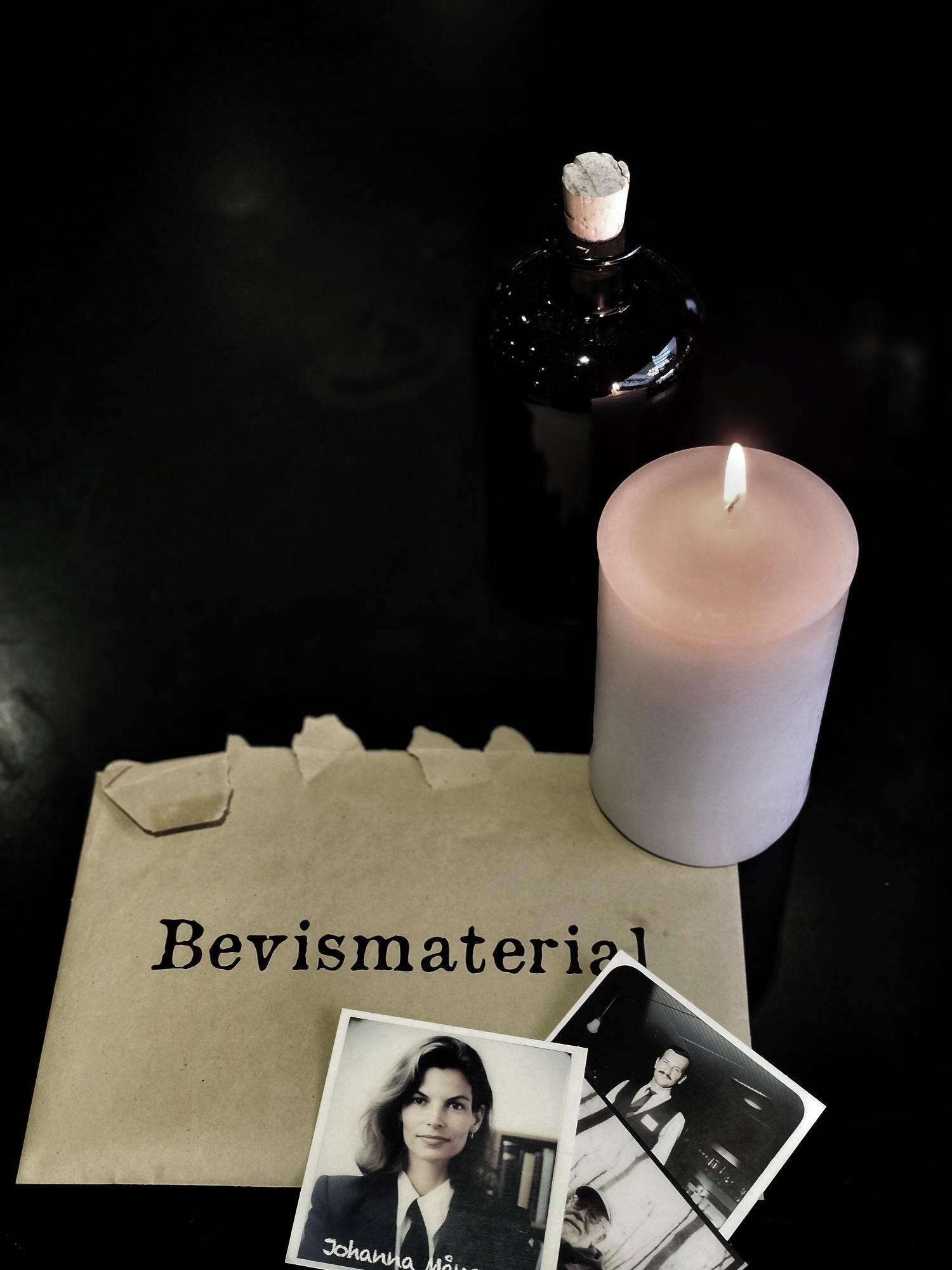 Une bougie, une bouteille et une carte sur laquelle est écrit le mot « Bevismaterial » sur une surface sombre.