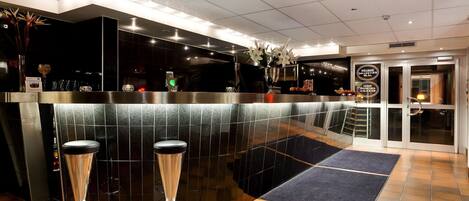 A modern bar area with a curved counter, two bar stools, and a glass door entrance.