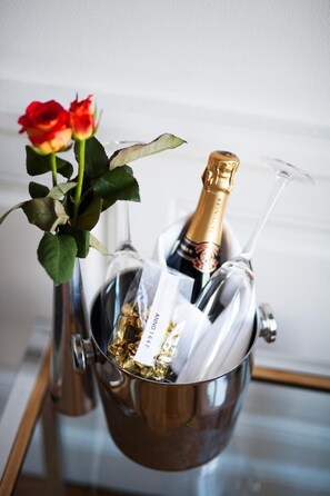 Una botella de champán en un balde de metal con una rosa y una copa.