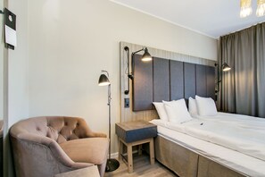 A modern hotel room with a large bed, a seating area, and a desk.