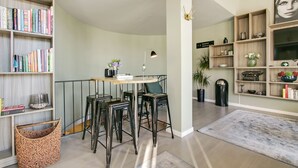 A modern living space with a dining area, bookshelves, a TV, and decorative items. - First Hotel Brommaplan (Bromma)