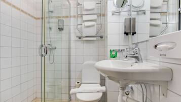 Un baño moderno con ducha envuelta en vidrio, inodoro blanco y lavabo con espejo.