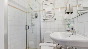 A modern bathroom with a glass shower enclosure, a white sink, and a toilet.