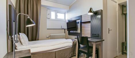 Una habitación pequeña con cama, escritorio, silla y televisor.