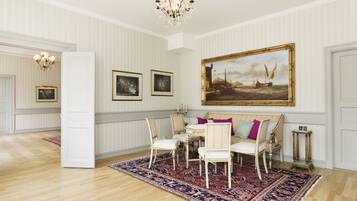 A room with a large painting, a chandelier, and a patterned rug.
