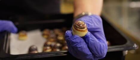 A chef in a white shirt and black apron holding a pastry.