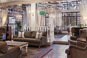 Una sala de estar acogedora con un sofá, sillones, una mesa de centro y una estantería.