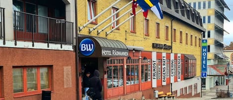 Un hotel con un letrero que dice "Hotel Rädmannen" y una bandera con una cruz azul y una cruz amarilla.