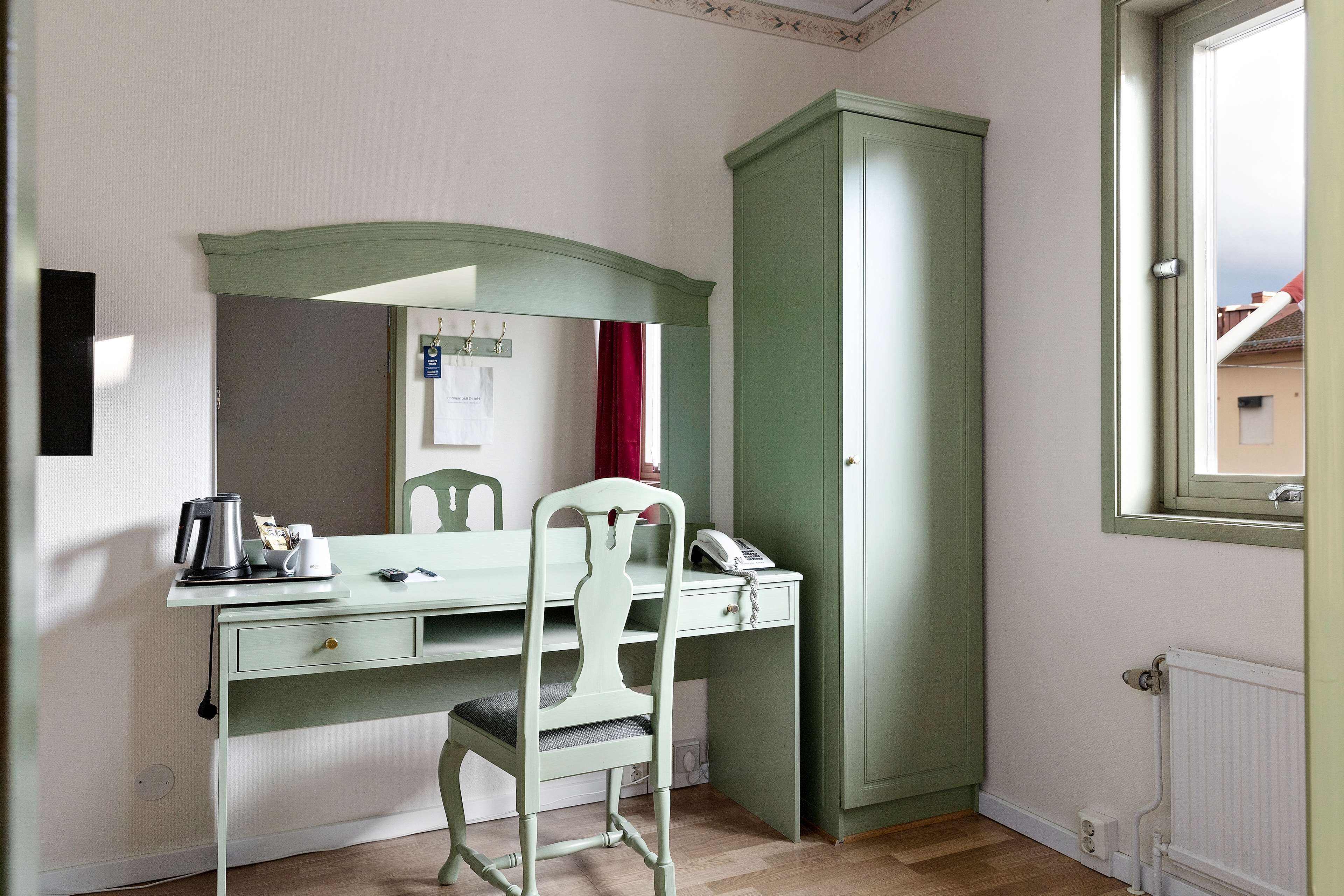 A room with a green desk, a chair, a radiator, and a window.