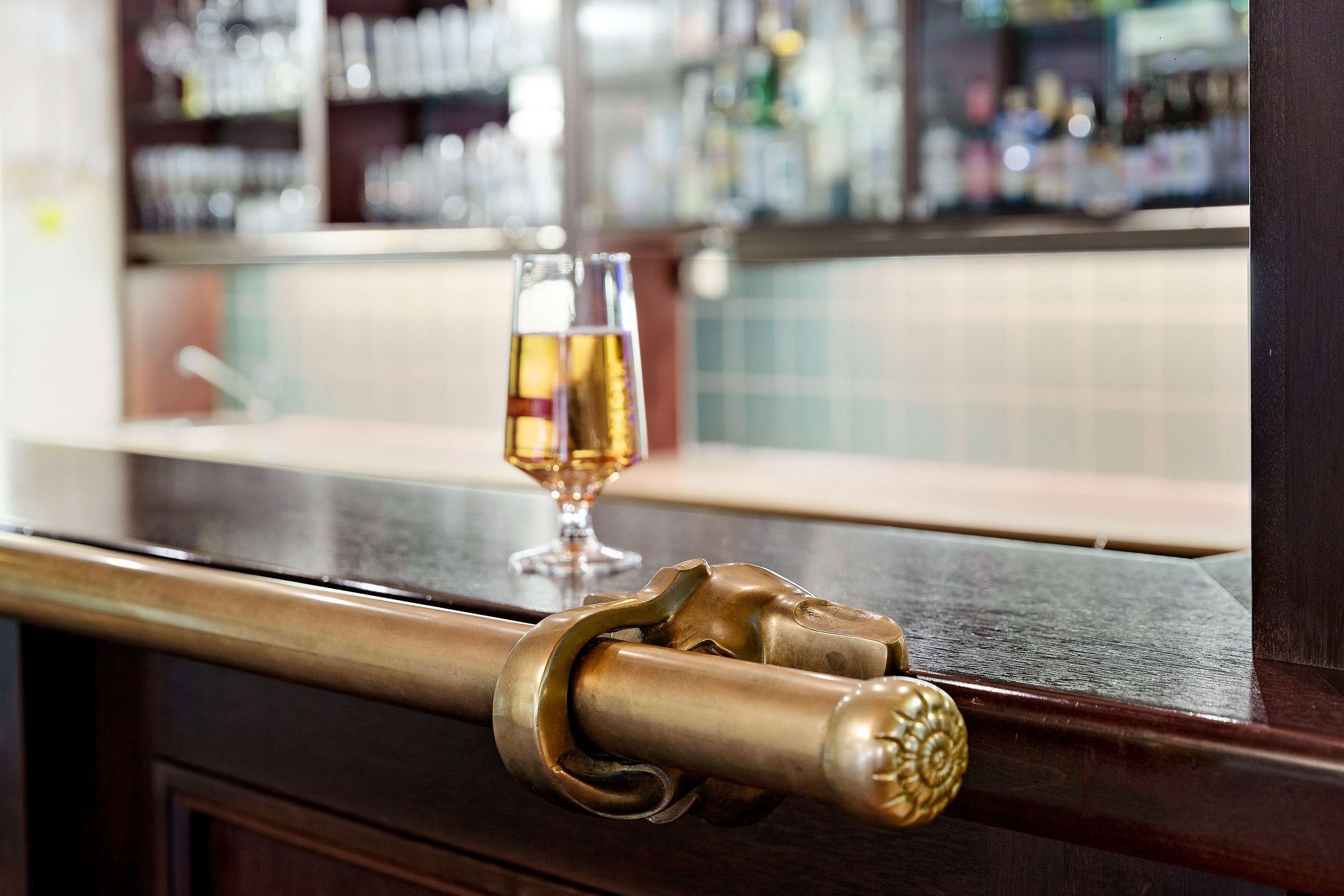 A bar area with a wooden counter and a glass of liquor.